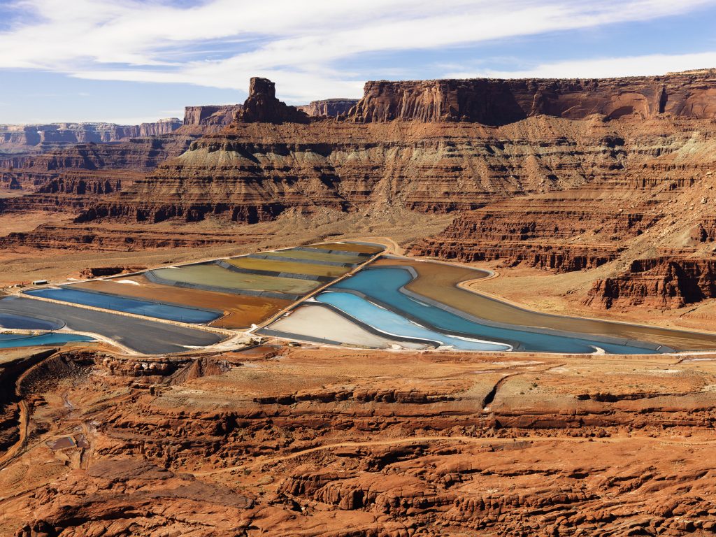 Aerial view of an arid, craggy landscape surrounding tailing ponds.